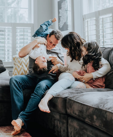 a couple playing with their children on a couch