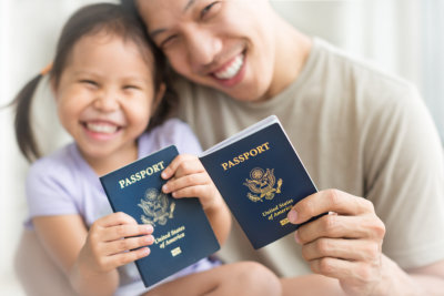 father and daughter smiling holding passports
